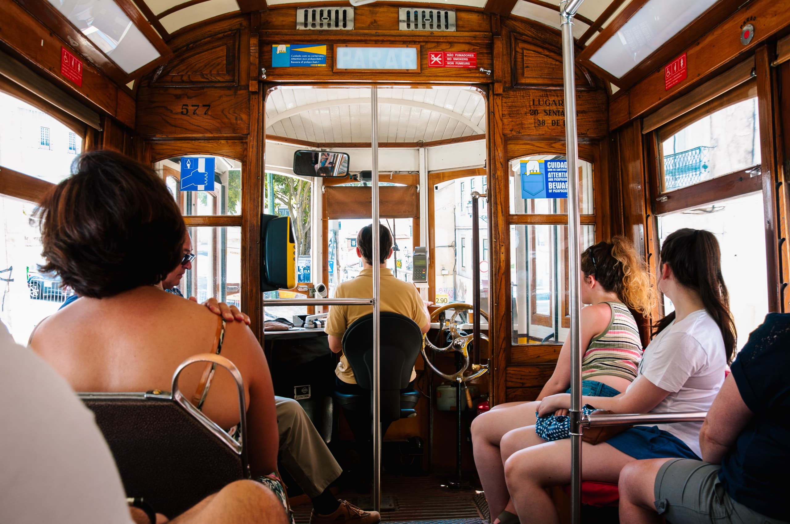 Interno di un tram storico di Lisbona con turisti in vacanza con Girolibero seduti. Viaggi avventura.